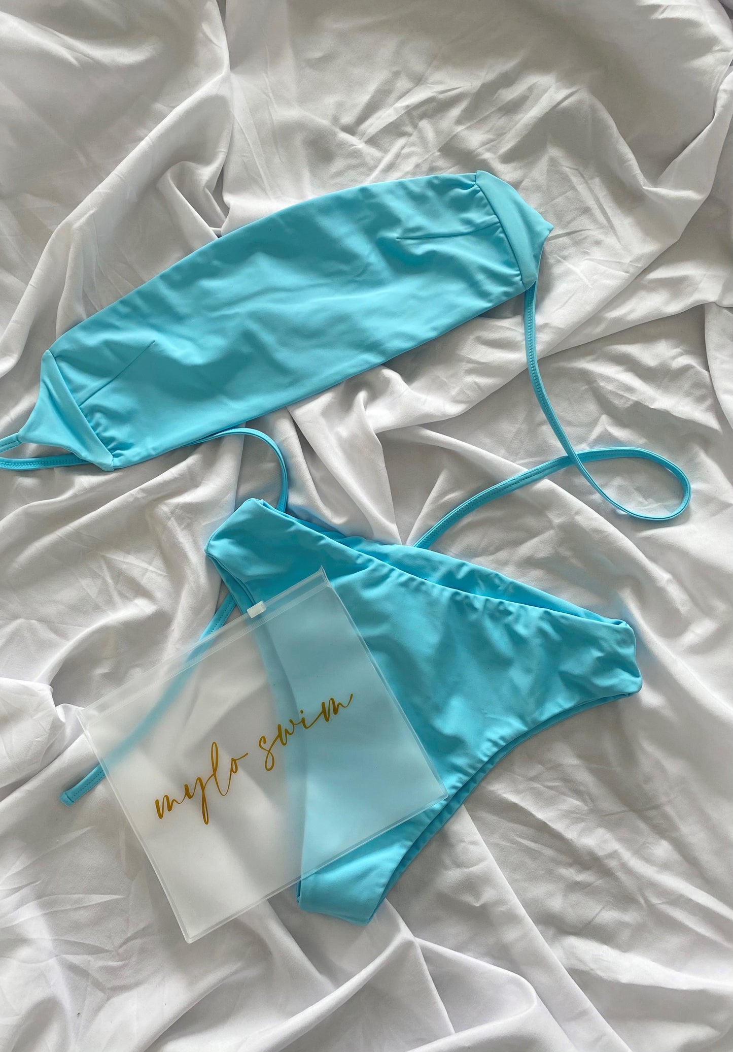 Biodegradable ziploc pouch for wet swimwear or beach items. Pouch has mylo swim scripted in gold across. Sitting with the ocen blue Amalfi strapless top and high waisted swimwear bottoms.